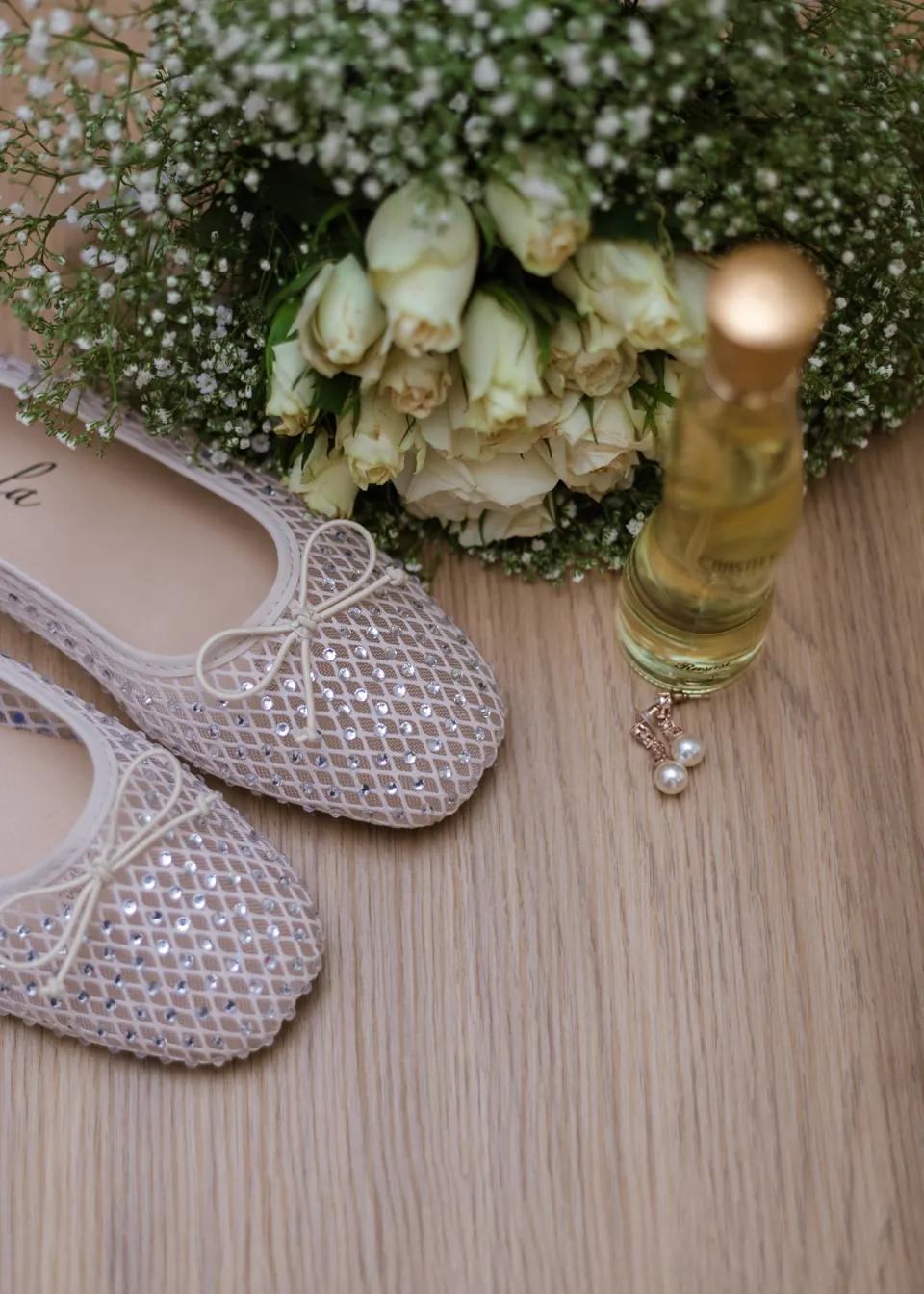 White bridal bouquet beside lace wedding shoes and earrings